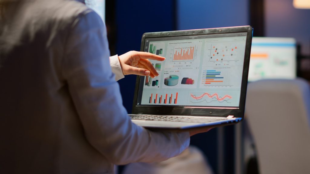 Back view of business woman analysing financial statistics holding laptop